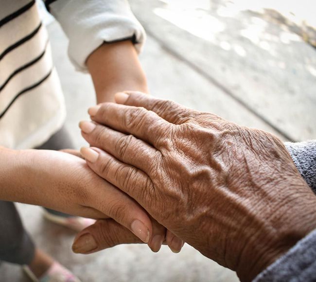 Un niño y una persona mayor se toman de la mano.