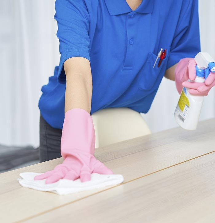 Una persona que lleva guantes rosas está limpiando una mesa.