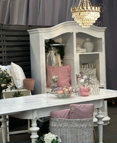 Ein weißer Tisch mit einem Korb darauf und einem Kronleuchter, der von der Decke hängt.