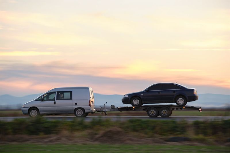 Auto wird auf dem Anhänger eines Kleinlasters transportiert