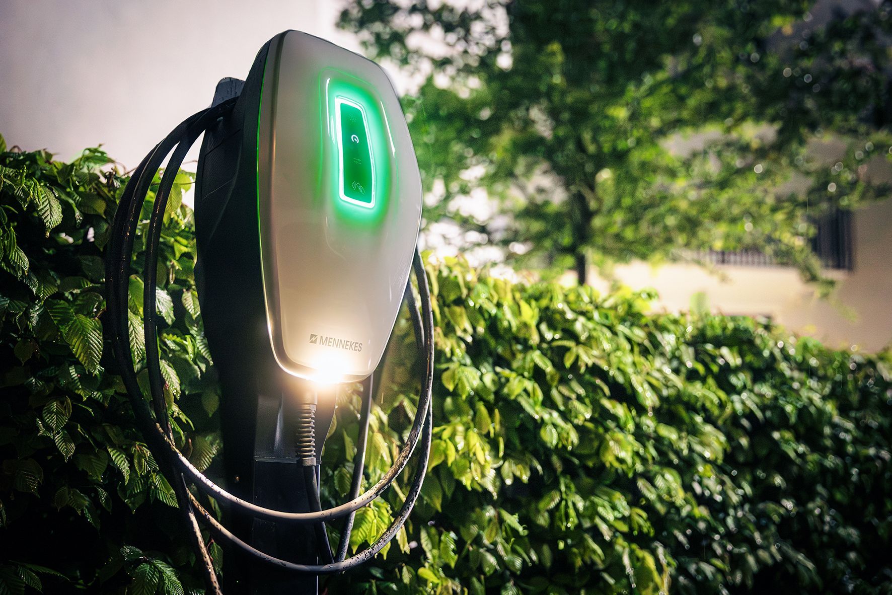 Zwei an einem Backsteinpfeiler montierte Ladestationen für Elektrofahrzeuge, an einer davon ist ein silbernes Auto angeschlossen.