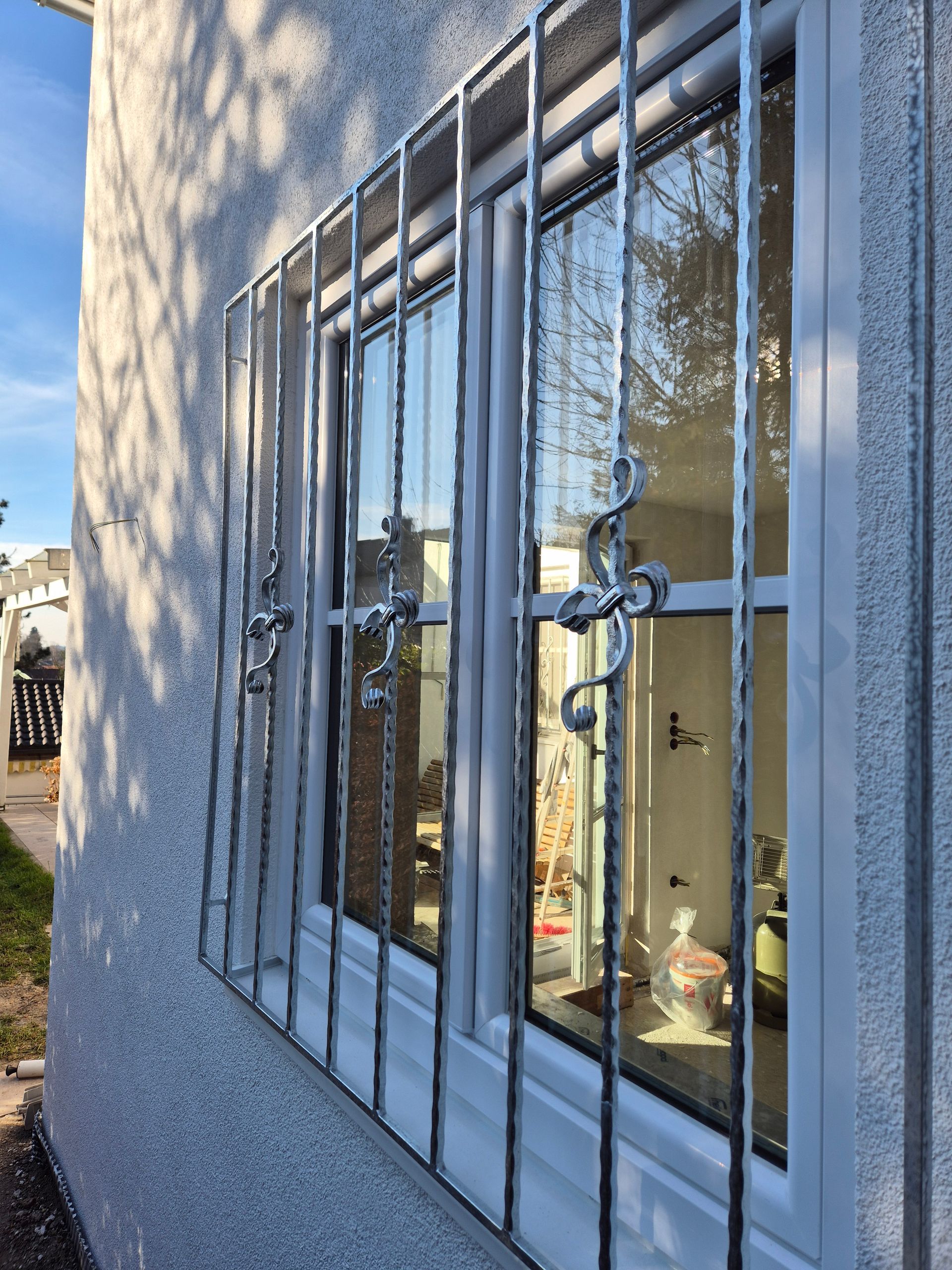 Metallgitter mit Verzierung vor einem Fenster 