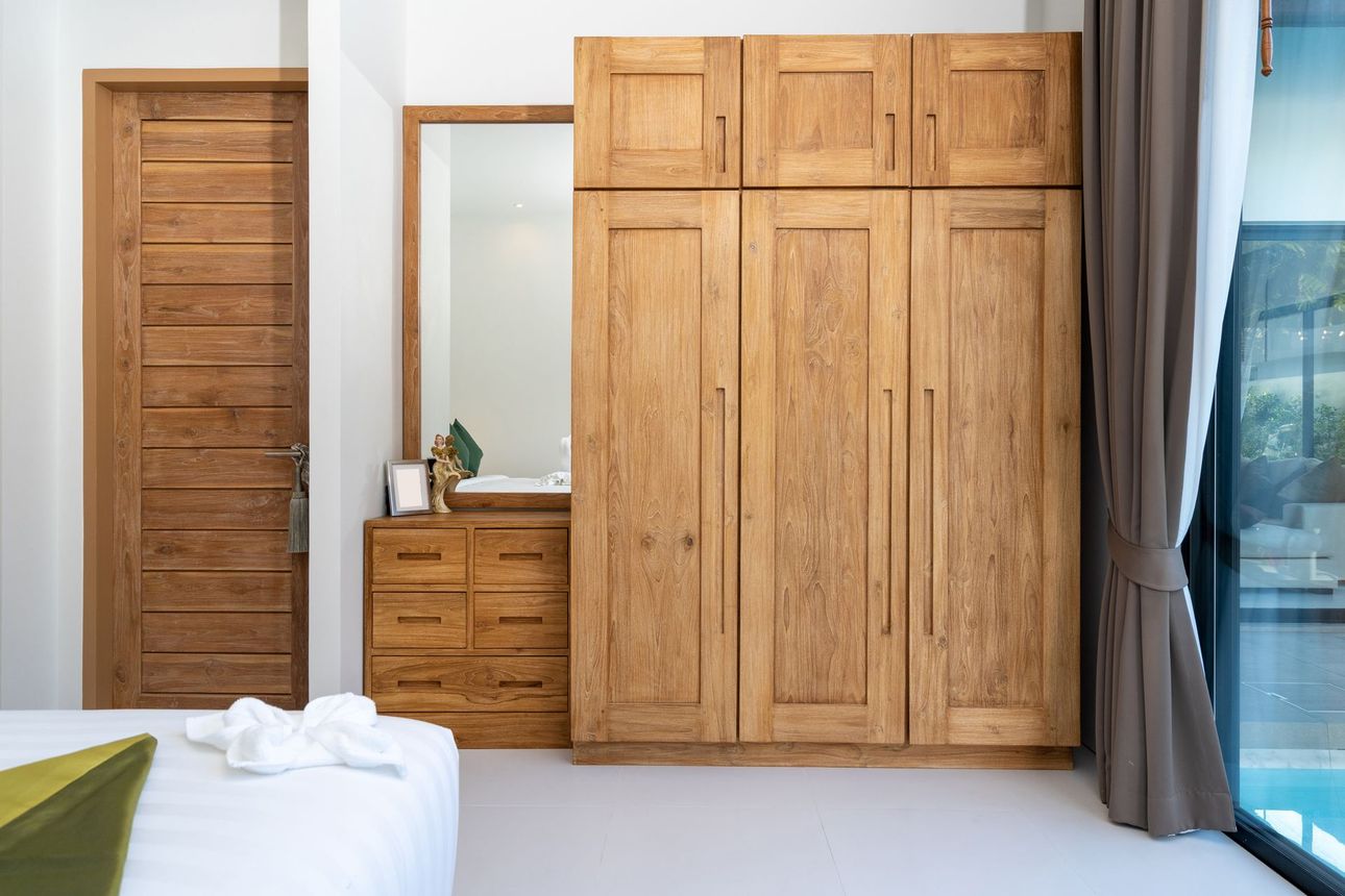 Chambre avec armoire en bois, porte, commode et un lit avec une serviette.