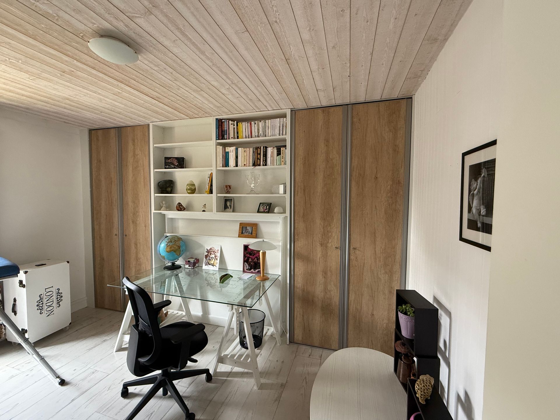 Placard en bois avec portes coulissantes, étagères intérieures, vêtements suspendus et éclairage au plafond.