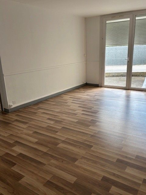Personne agenouillée, installant un parquet à chevrons avec des gants dans une pièce.