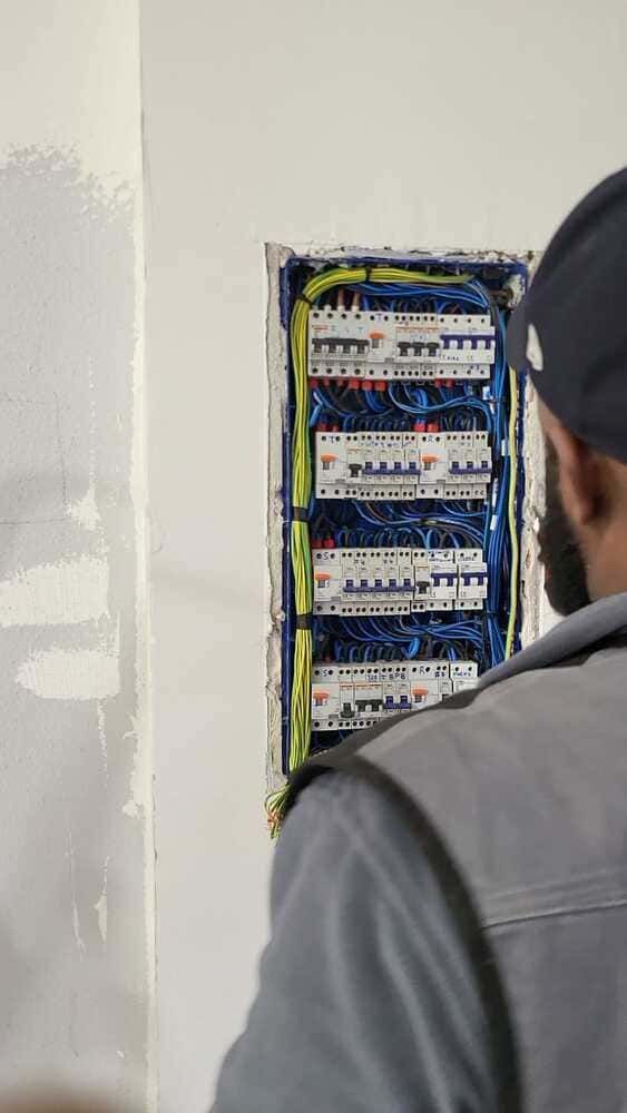 Electricista trabajando en un cuadro eléctrico en una pared