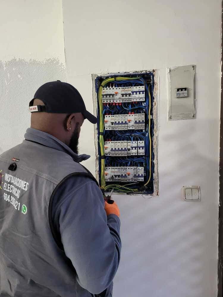 Electricista trabajando en panel eléctrico montado en la pared.