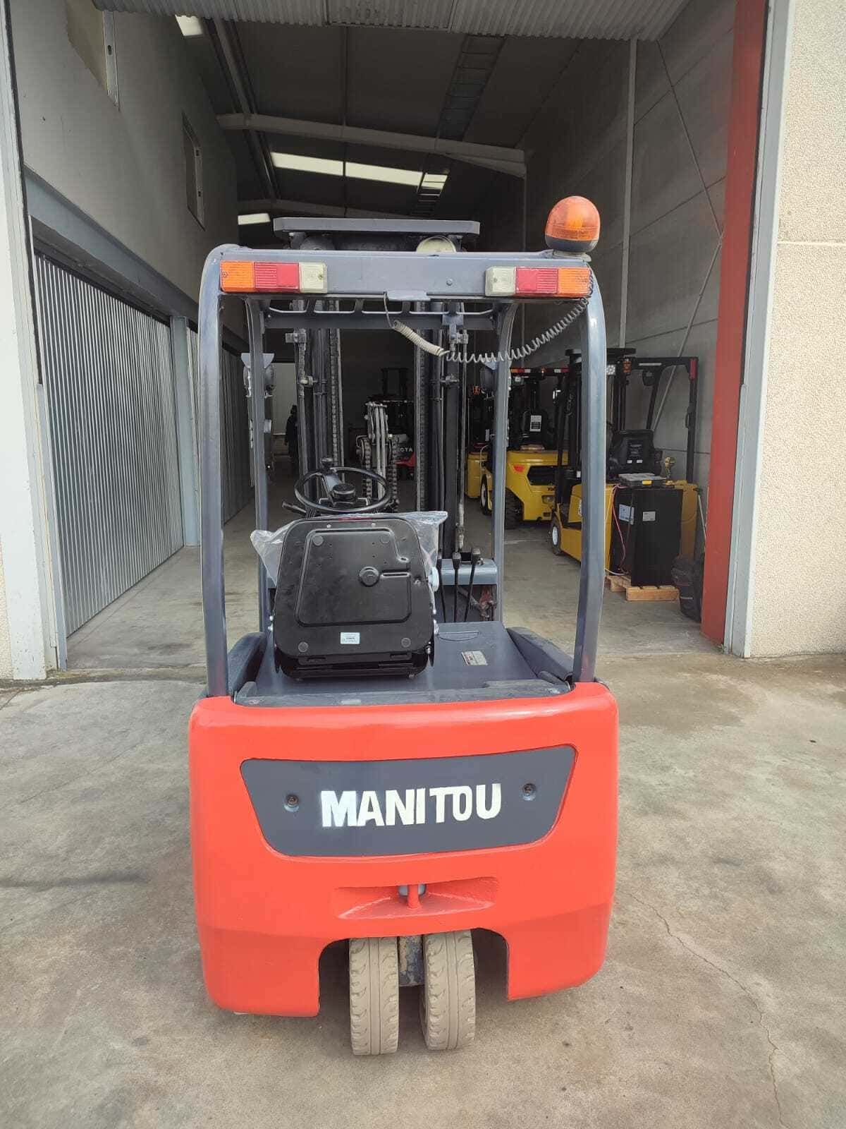 Vista trasera de una carretilla elevadora Manitou de color naranja estacionada dentro de un almacén industrial.