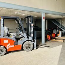 Una carretilla elevadora está estacionada en un garaje al lado de unas escaleras.