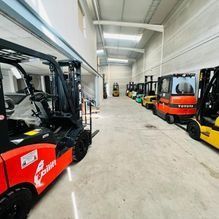Una fila de carretillas elevadoras están estacionadas en un almacén.