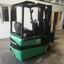 Una carretilla elevadora verde está estacionada en un garaje.