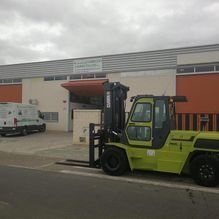 Una carretilla elevadora verde está estacionada frente a un edificio.