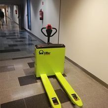 Una transpaleta amarilla está parada en un pasillo.