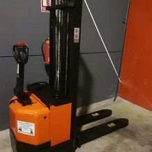 Una carretilla elevadora está parada en un almacén al lado de un extintor de incendios.