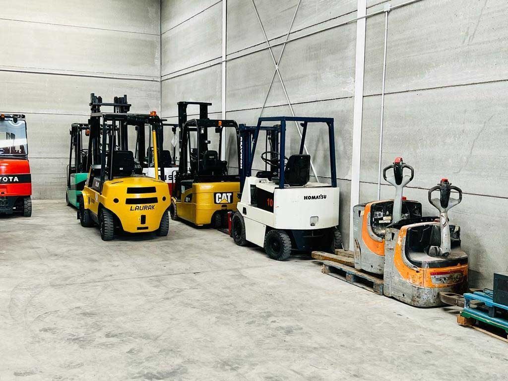 Una fila de carretillas elevadoras están estacionadas en un almacén.