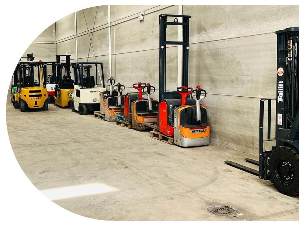 Una fila de carretillas elevadoras están estacionadas en un almacén.