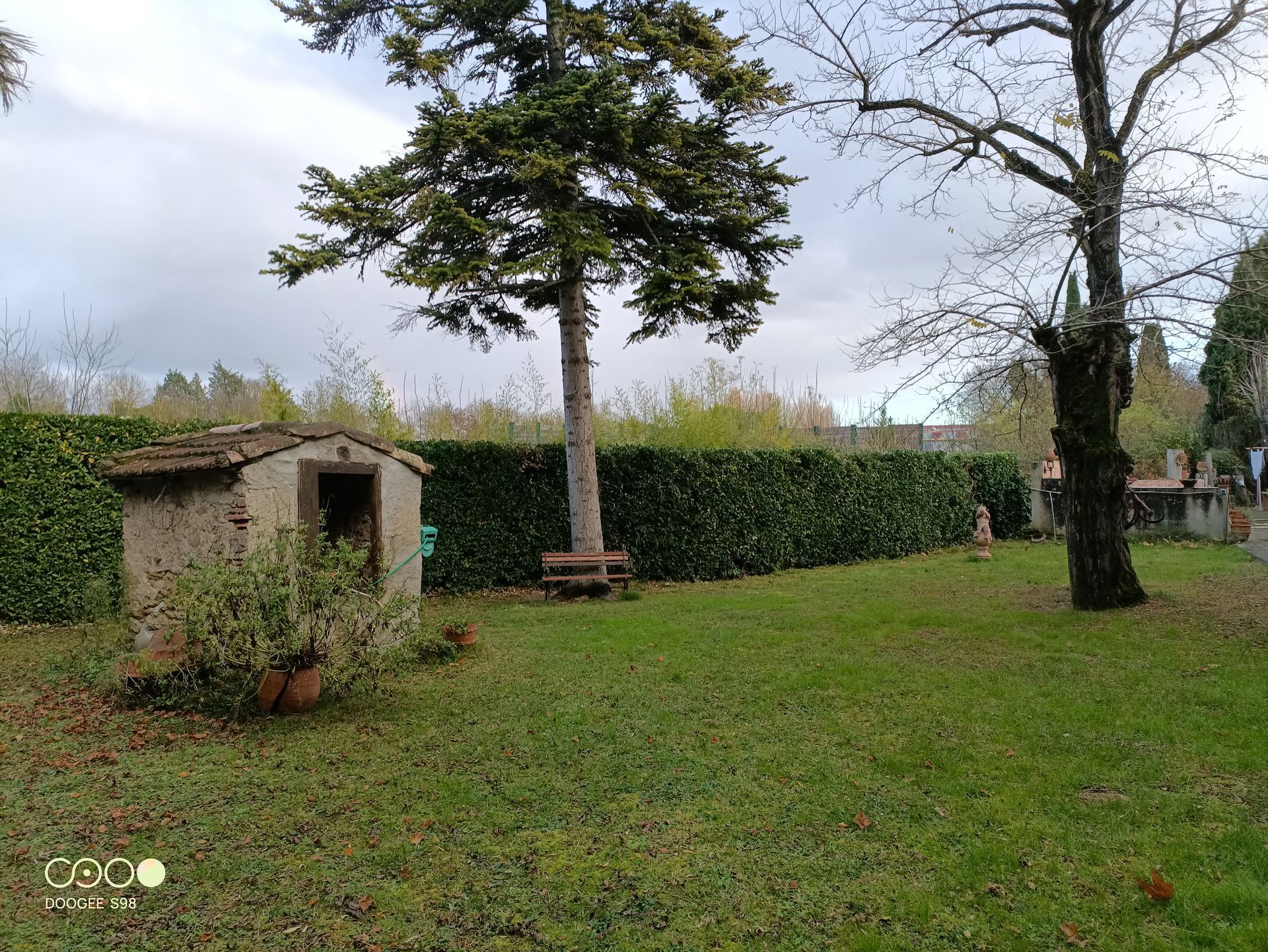 Un abri en pierre, des arbres et une pelouse verte sous un ciel nuageux.