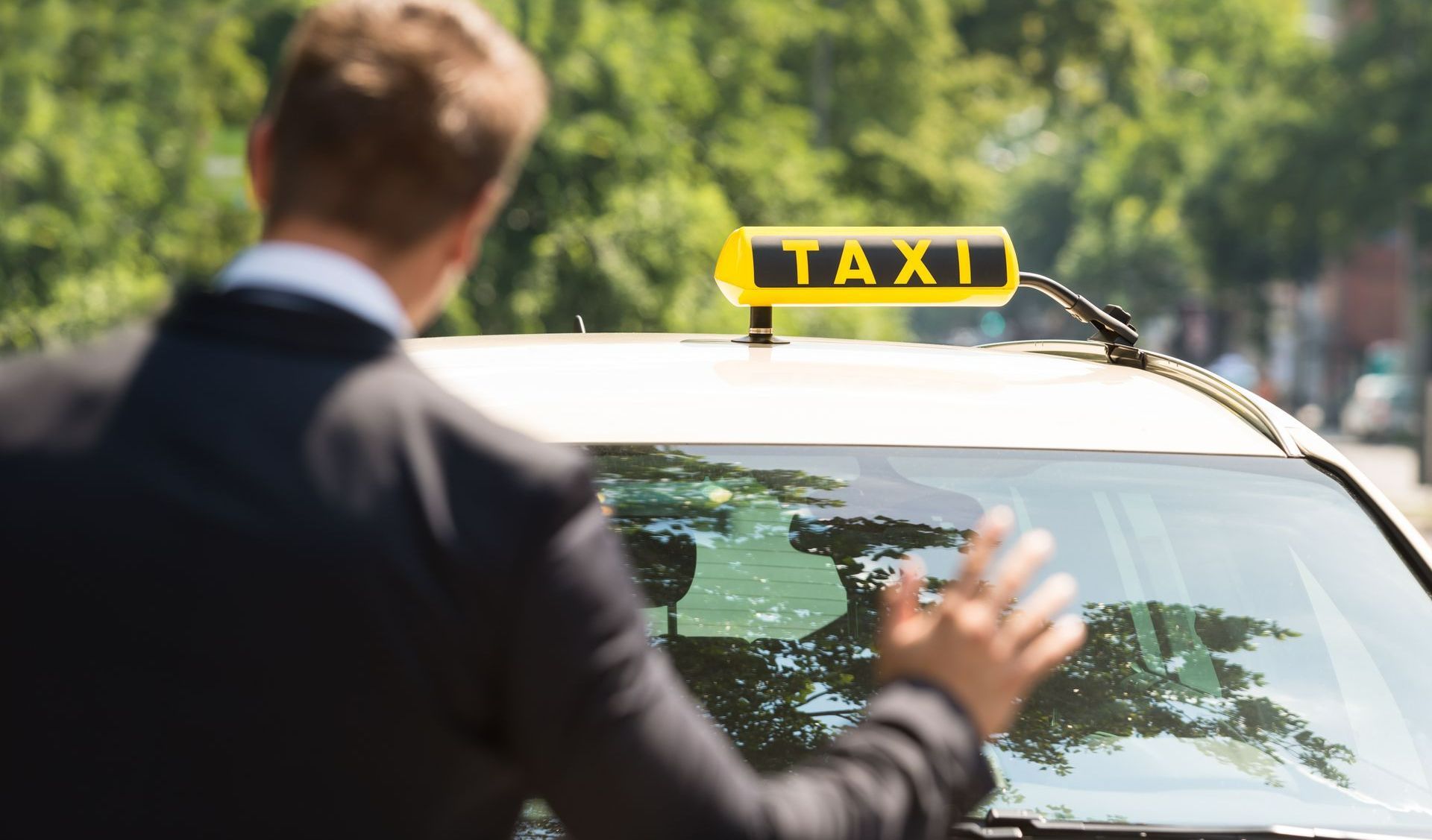 Un homme en costume levant la main vers un taxi