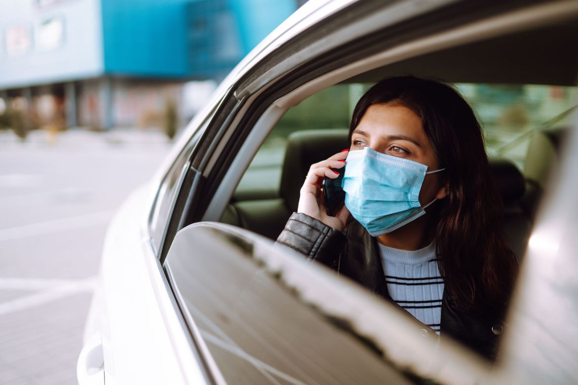 Une femme portant un masque téléphonant à l'arrière d'un taxi