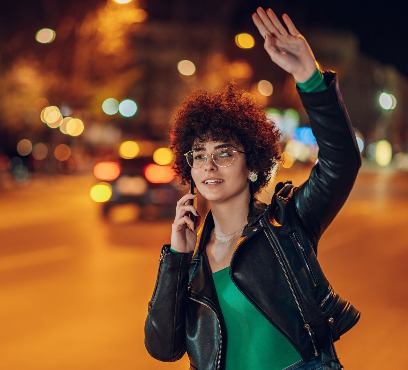 Une femme qui lève le bras pour appeler un taxi de nuit