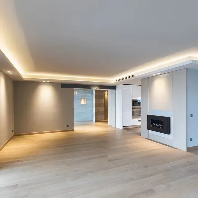 Una sala de estar vacía con pisos de madera y chimenea.