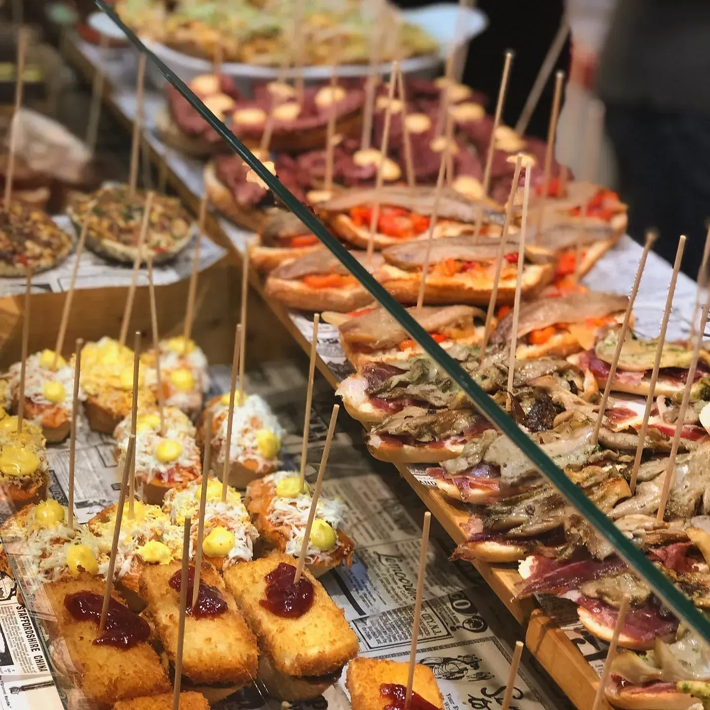 Variedad de pintxos (tapas vascas) en exposición, ensartados con palillos.