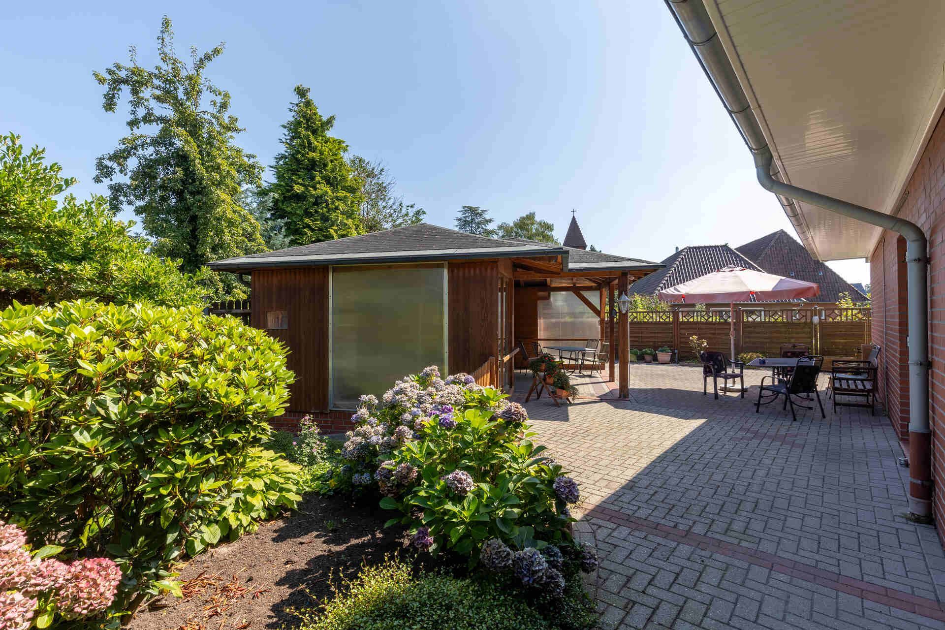 Ein Altenwohn- und Pflegeheim mit einer Terrasse und einem Pavillon im Hinterhof.