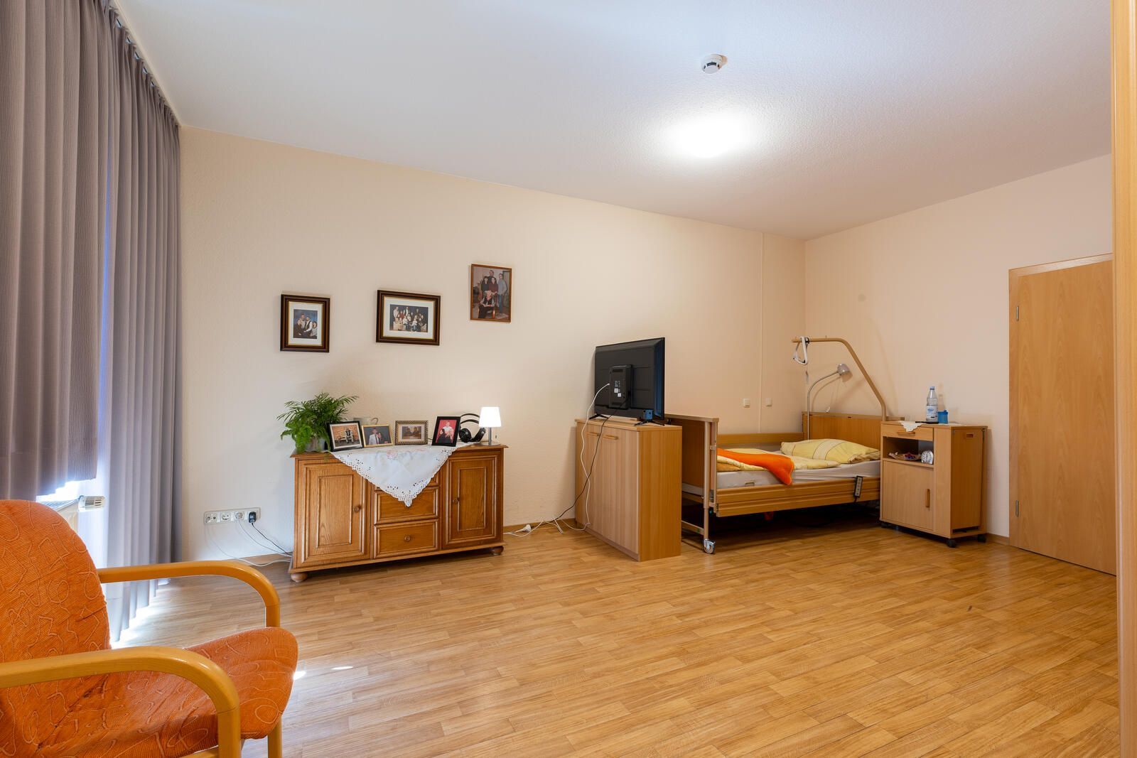 Ein Schlafzimmer mit Bett, Kommode, Stuhl und Fernseher.