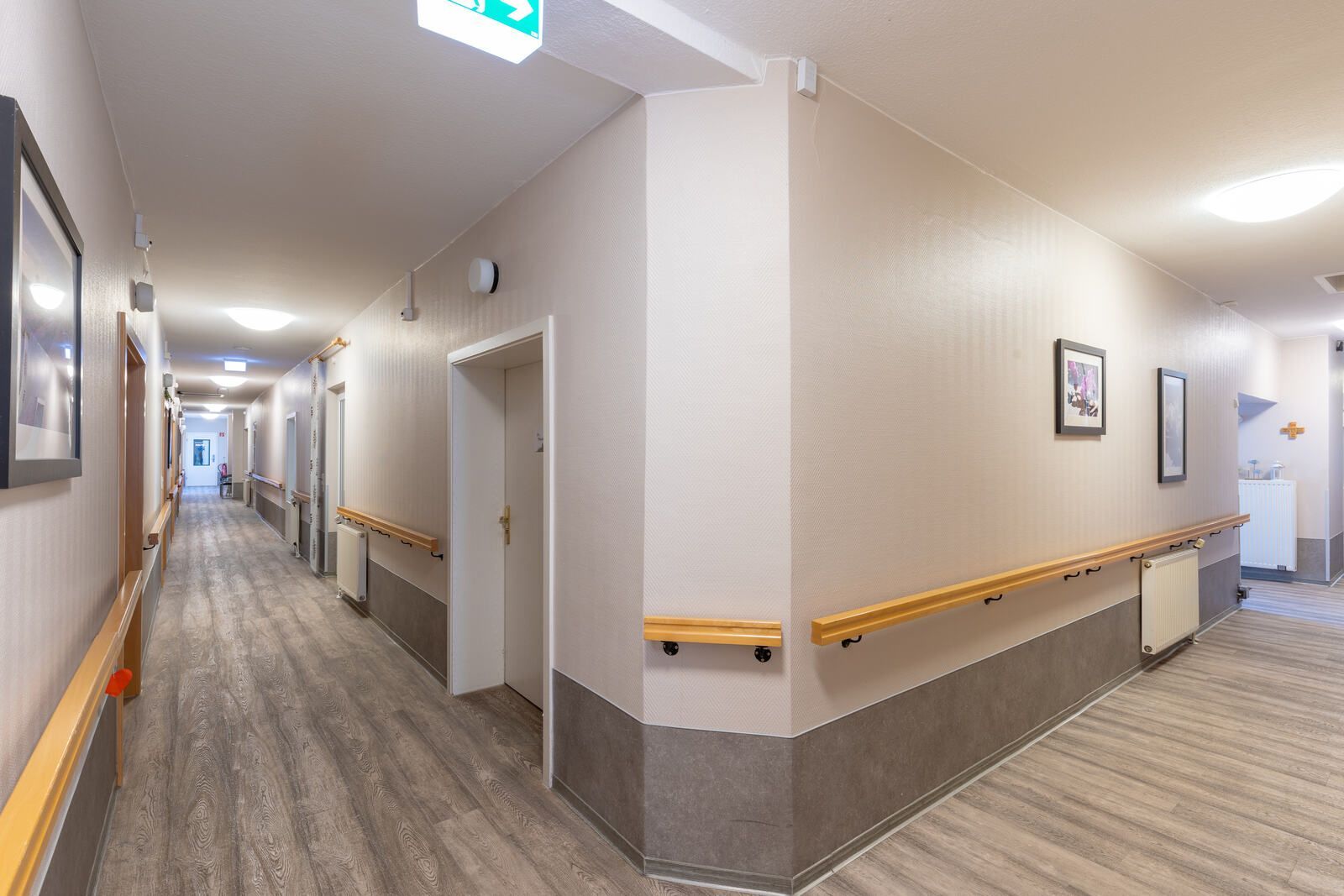 Ein langer Flur in einem Altenwohn- und Pflegeheim mit Holzböden und -wänden.