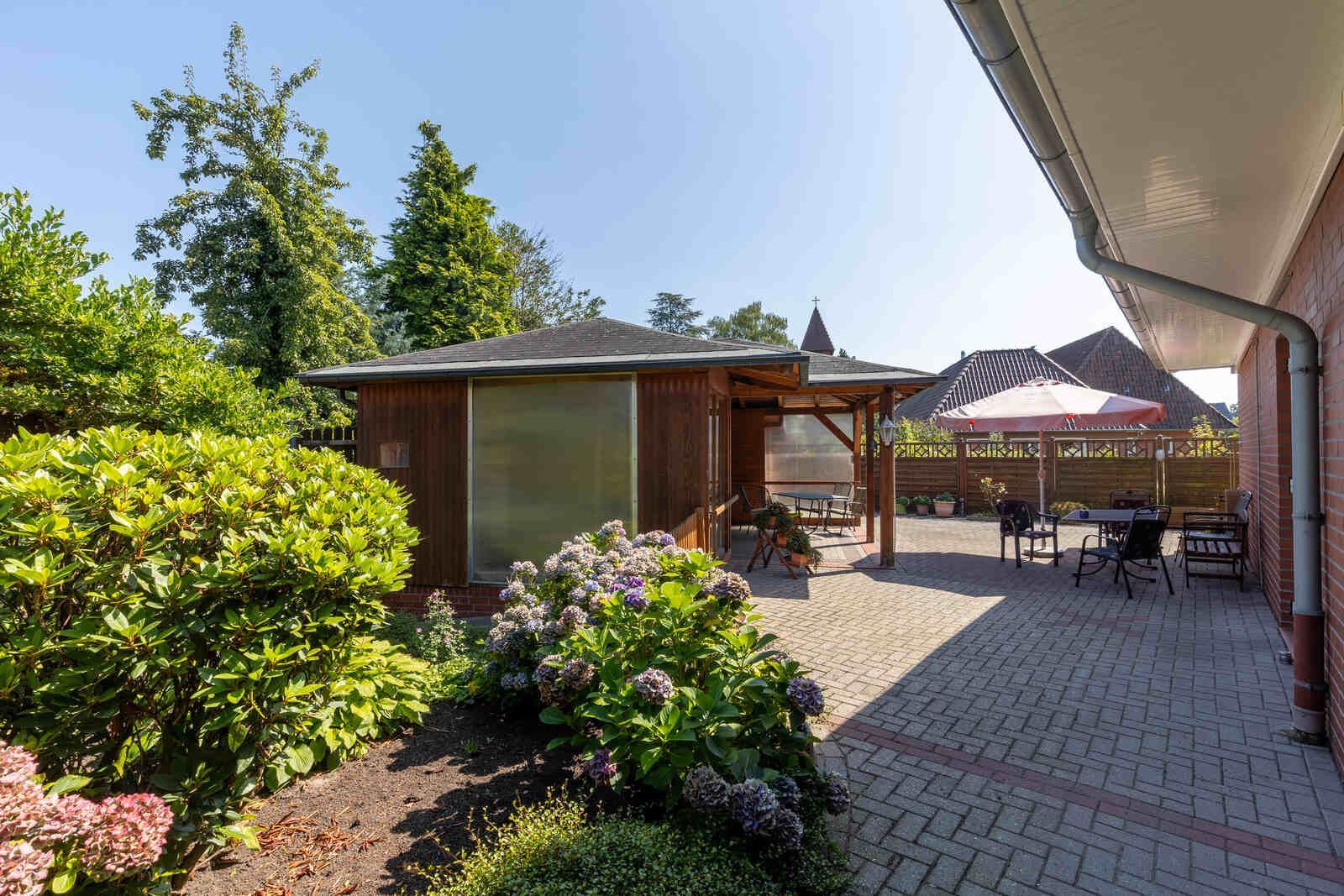 Ein Altenwohn- und Pflegeheim mit einer Terrasse und einem Pavillon im Hinterhof.