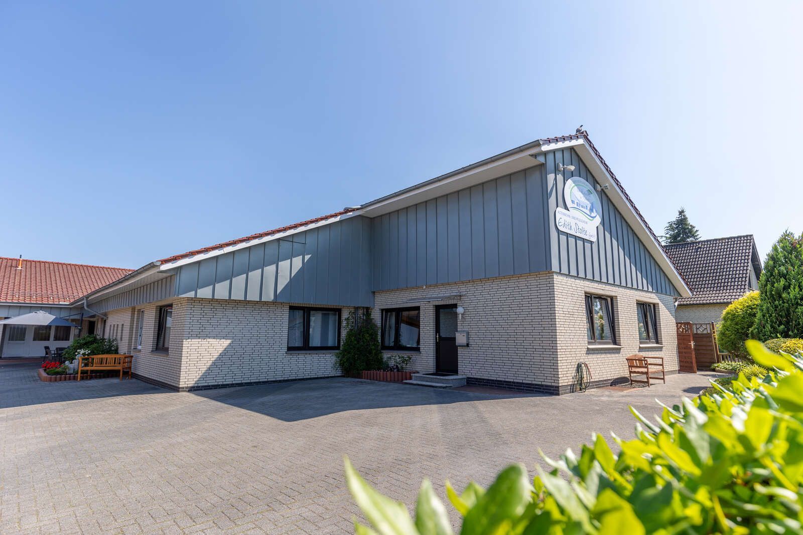 Ein großes Altenwohn- und Pflegeheim mit vielen Fenstern und einer Bank davor.