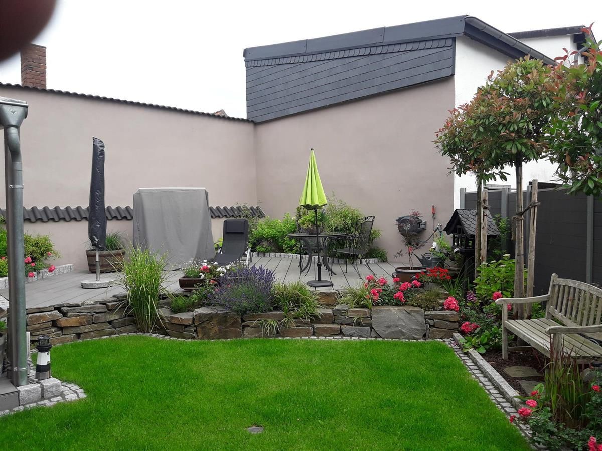 Ein Hinterhof mit einem grünen Sonnenschirm und einer Bank