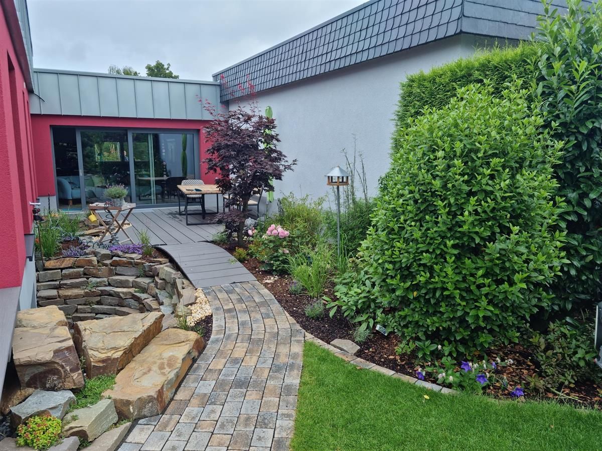 Ein Ziegelweg führt zu einer Terrasse mit Tisch und Stühlen