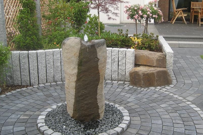 Ein Steinbrunnen in der Mitte eines Ziegelwegs