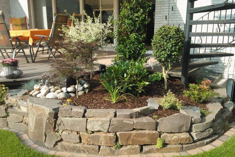 Ein Garten mit Steinen und Pflanzen vor einem Haus