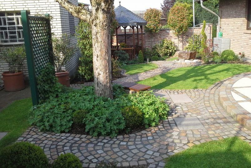 Ein gemauerter Gehweg, der zu einem Pavillon in einem Garten führt