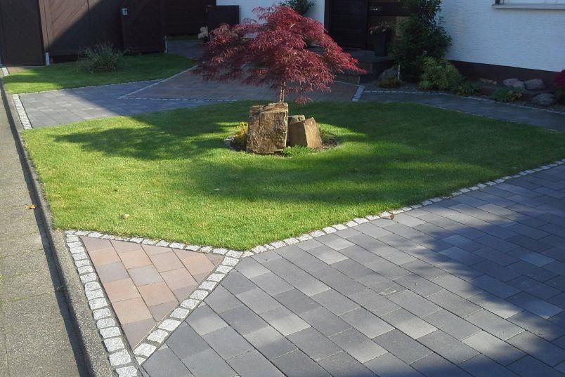 Eine gepflasterte Auffahrt mit einem Baum in der Mitte