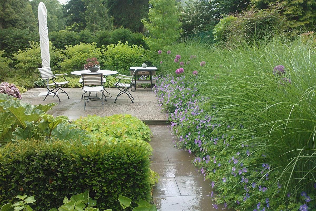 Ein Tisch und Stühle in einem Garten mit lila Blumen