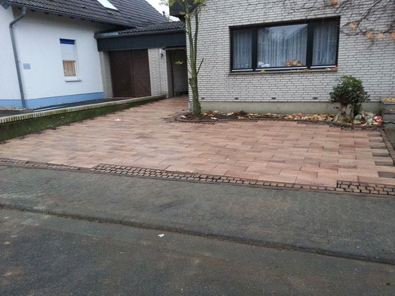 Eine gemauerte Auffahrt vor einem weißen Backsteinhaus