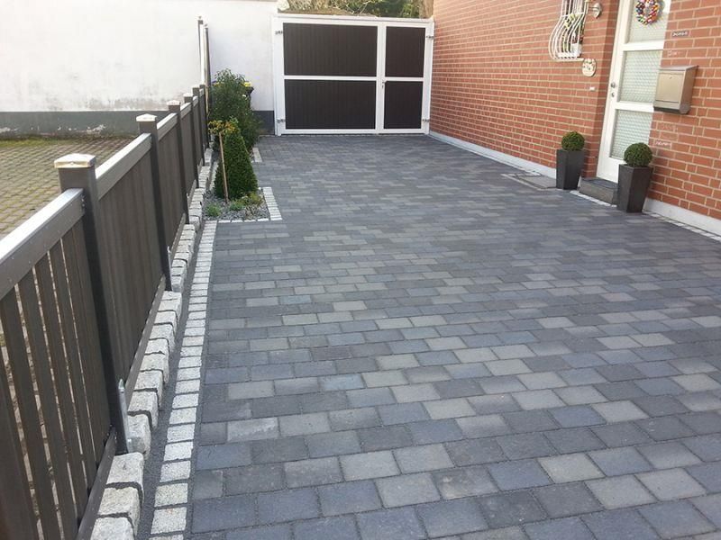 Eine gemauerte Auffahrt mit einem Zaun an der Seite