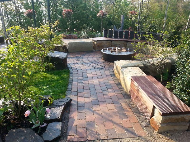 Ein gemauerter Gehweg mit einer Holzbank in der Mitte