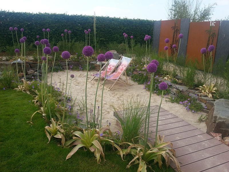 Ein Garten mit lila Blumen und einem Stuhl in der Mitte