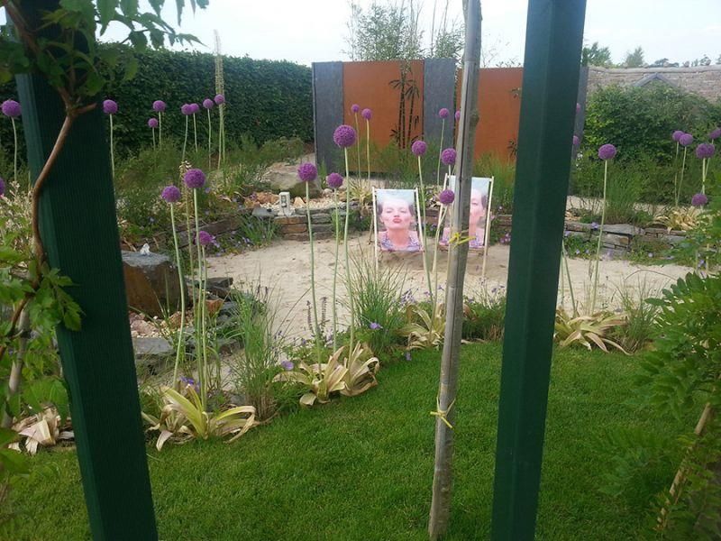 Ein Garten mit lila Blumen und Stühlen darin