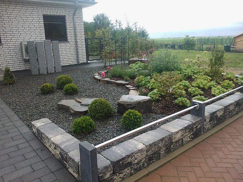 Ein gemauerter Gehweg, der zu einem Haus mit einem Garten davor führt