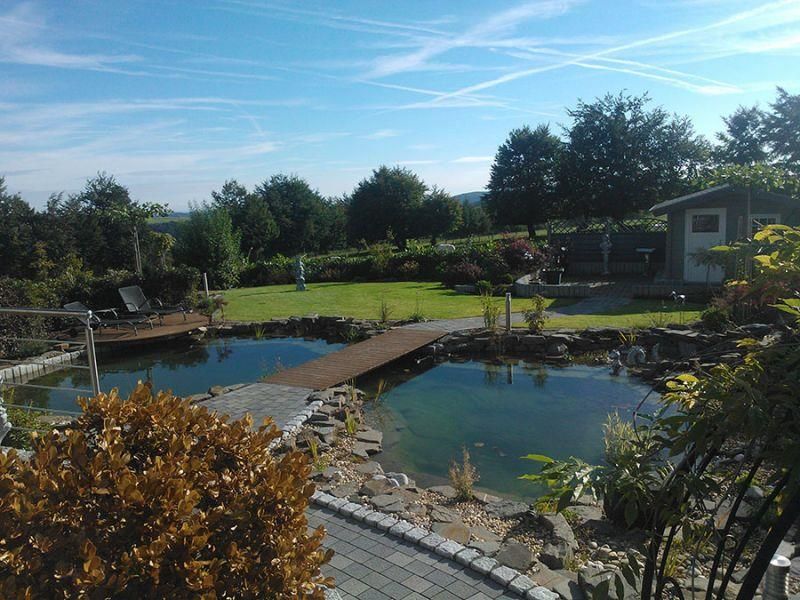 Ein Teich in einem Garten mit einer Holzbrücke darüber