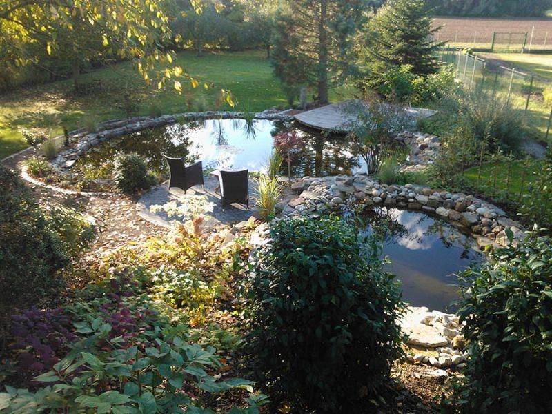 Ein Teich in einem Garten mit einem Pavillon im Hintergrund