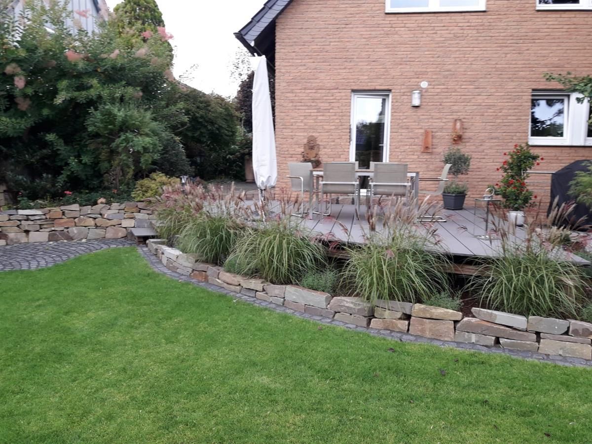 Ein Backsteinhaus mit Terrasse und Rasen davor