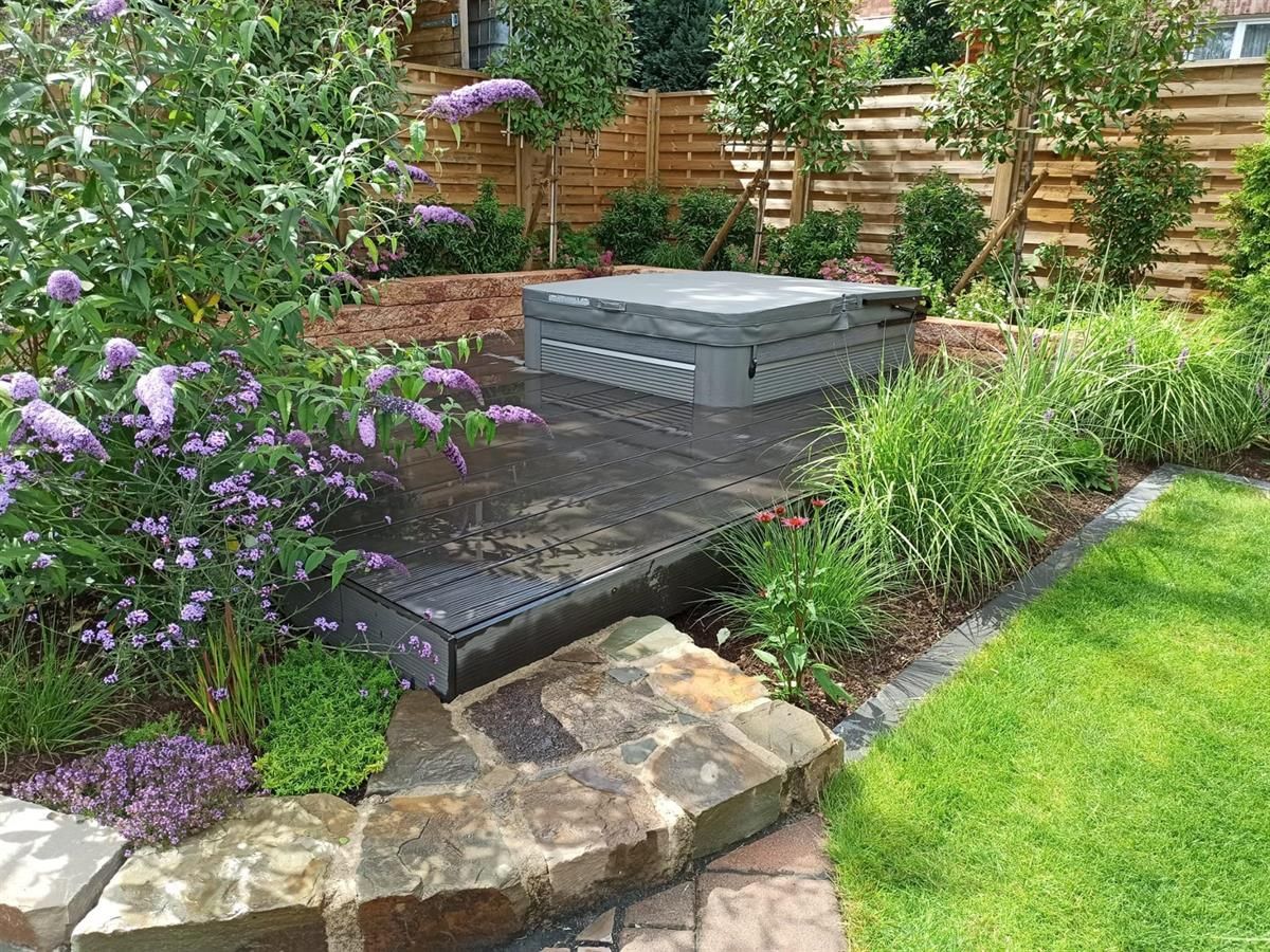 Ein Garten mit lila Blumen und einem Whirlpool in der Mitte