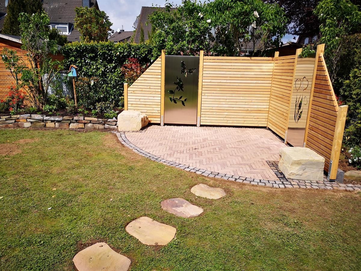 Ein Holzzaun umgibt eine Terrasse in einem Hinterhof