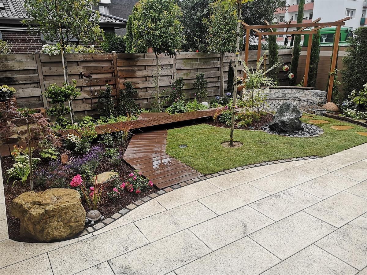 Ein Garten mit einem Steinweg und einem Holzzaun